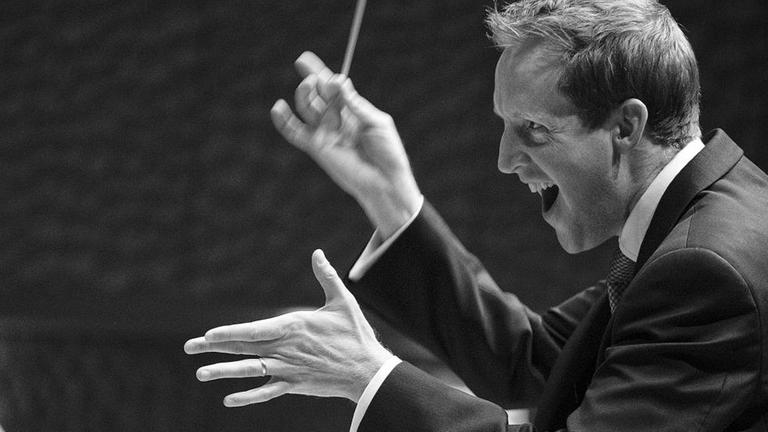 Der Dirigent Justin Doyle dirigiert ein Orchester Der Dirigent Justin Doyle dirigiert ein Orchester