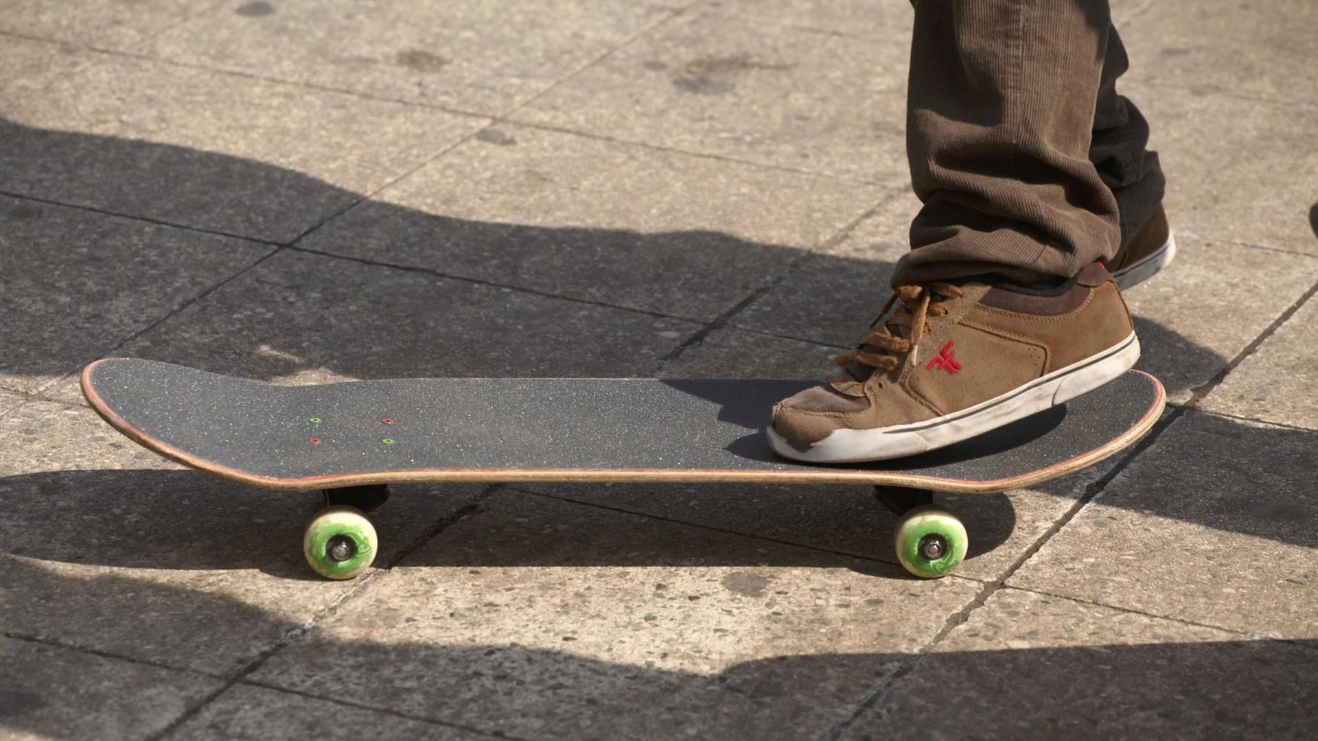 Ein Skateboardfahrer in Cordhose steht auf seinem Board. Ein Skateboardfahrer in Cordhose steht auf seinem Board.