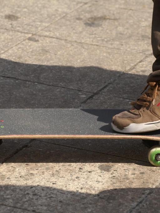 Ein Skateboardfahrer in Cordhose steht auf seinem Board.