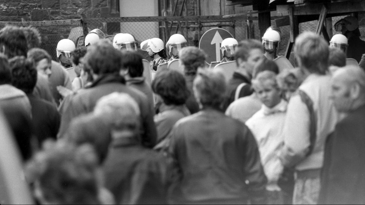Am Sonnabend, dem 7. Oktober 1989 - dem Nationalfeiertag zur Gründung der DDR - und zwei Tage vor der historischen Montagsdemonstration mit über 70.000 Teilnehmern auf dem Karl-Marx-Platz stehen Bürgerinnen und Bürger von Leipzig ganz ruhig auf dem Nikolaikirchhof vor der Nikolaikirche in Leipzig zusammen, der von Polizisten in alle Himmelsrichtungen abgeriegelt ist. Am Sonnabend, dem 7. Oktober 1989 - dem Nationalfeiertag zur Gründung der DDR - und zwei Tage vor der historischen Montagsdemonstration mit über 70.000 Teilnehmern auf dem Karl-Marx-Platz stehen Bürgerinnen und Bürger von Leipzig ganz ruhig auf dem Nikolaikirchhof vor der Nikolaikirche in Leipzig zusammen, der von Polizisten in alle Himmelsrichtungen abgeriegelt ist.