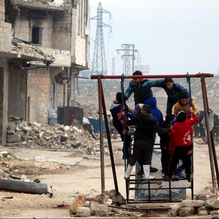 Kinder spielen in Aleppo vor zerstörten Gebäuden