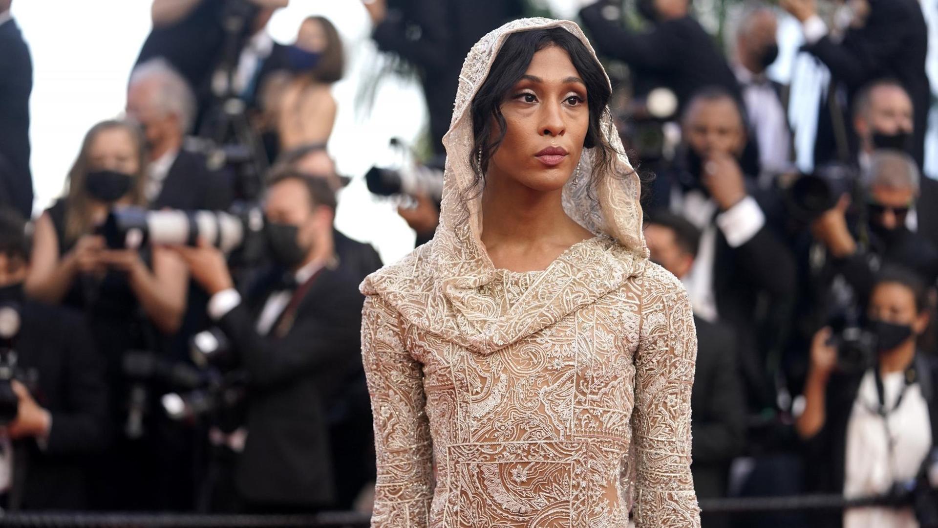 Eine junge Frau posiert auf dem rotem Teppich für die Fotografen, sie trägt ein langes, enganliegendes cremefarbenes Spitzenkleid mit Kapuze. Es handelt sich um die Schauspielerin Mj Rodriguez. Eine junge Frau posiert auf dem rotem Teppich für die Fotografen, sie trägt ein langes, enganliegendes cremefarbenes Spitzenkleid mit Kapuze. Es handelt sich um die Schauspielerin Mj Rodriguez.