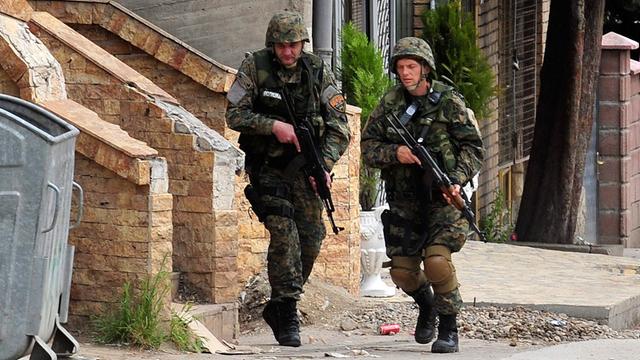 Zwei mit Gewehren bewaffnete mazedonische Polizisten laufen durch eine Straße von Kumanovo.