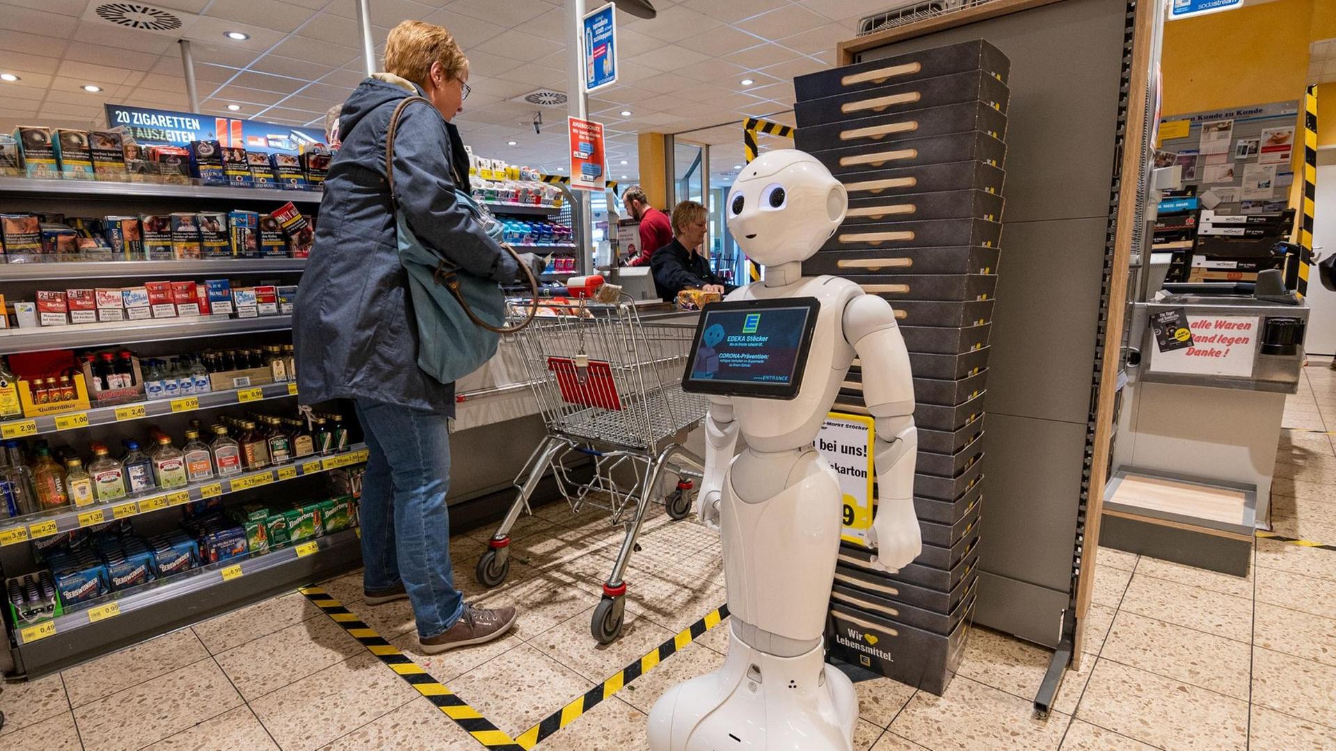 In Nordrhein-Westfalen steht der Pflegeroboter «Pepper» im Kassenbereich des Supermarktes und weist Kunden darauf hin, Abstand zu halten. In Nordrhein-Westfalen steht der Pflegeroboter «Pepper» im Kassenbereich des Supermarktes und weist Kunden darauf hin, Abstand zu halten.