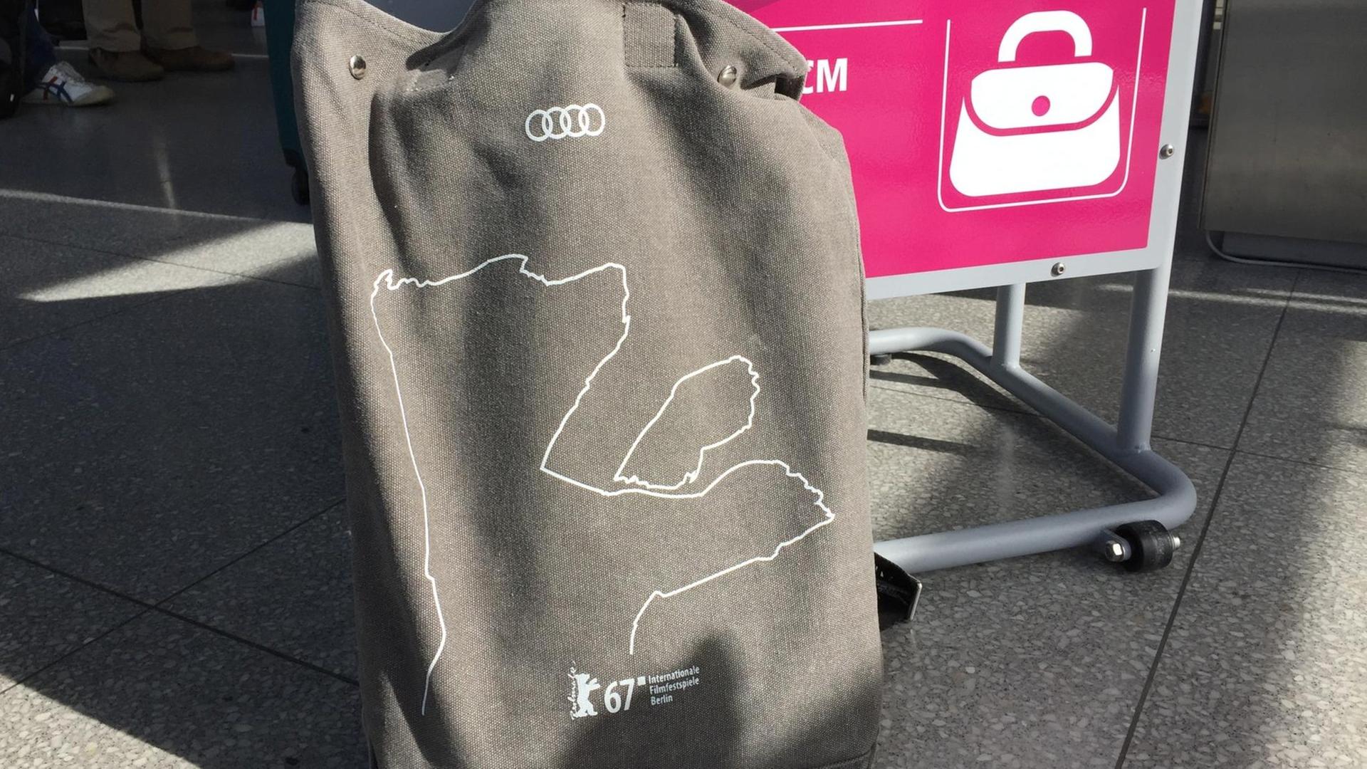 Ein grauer Rucksack mit dem Berlinale-Logo steht an einem Flughafen vor der Gepäckkontrolle.
