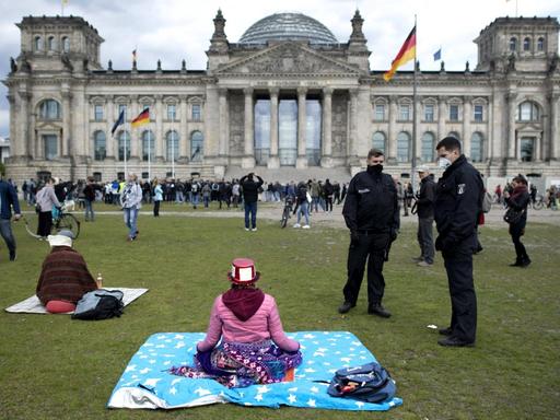 Polizisten fordern eine meditierende Frau während einer sogenannten Hygienedemo vor dem Reichstagsgebäude in Berlin auf, den Platz zu verlassen.