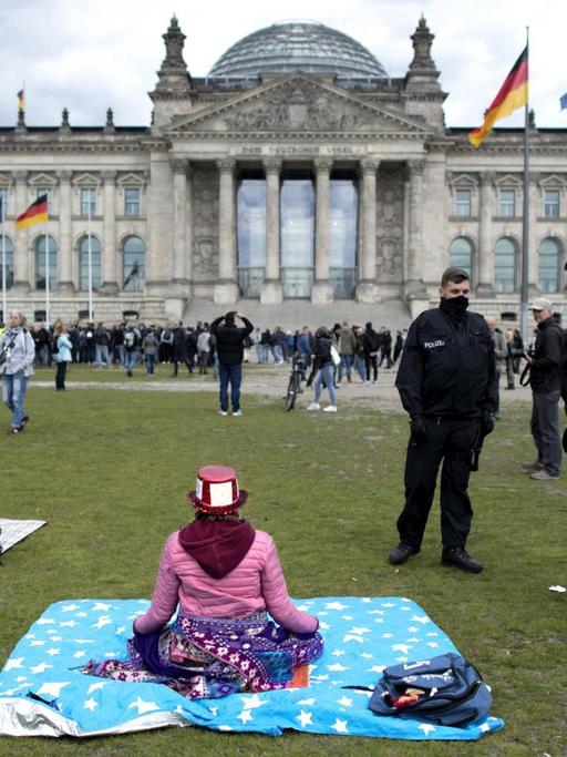 Polizisten fordern eine meditierende Frau während einer sogenannten Hygienedemo vor dem Reichstagsgebäude in Berlin auf, den Platz zu verlassen.