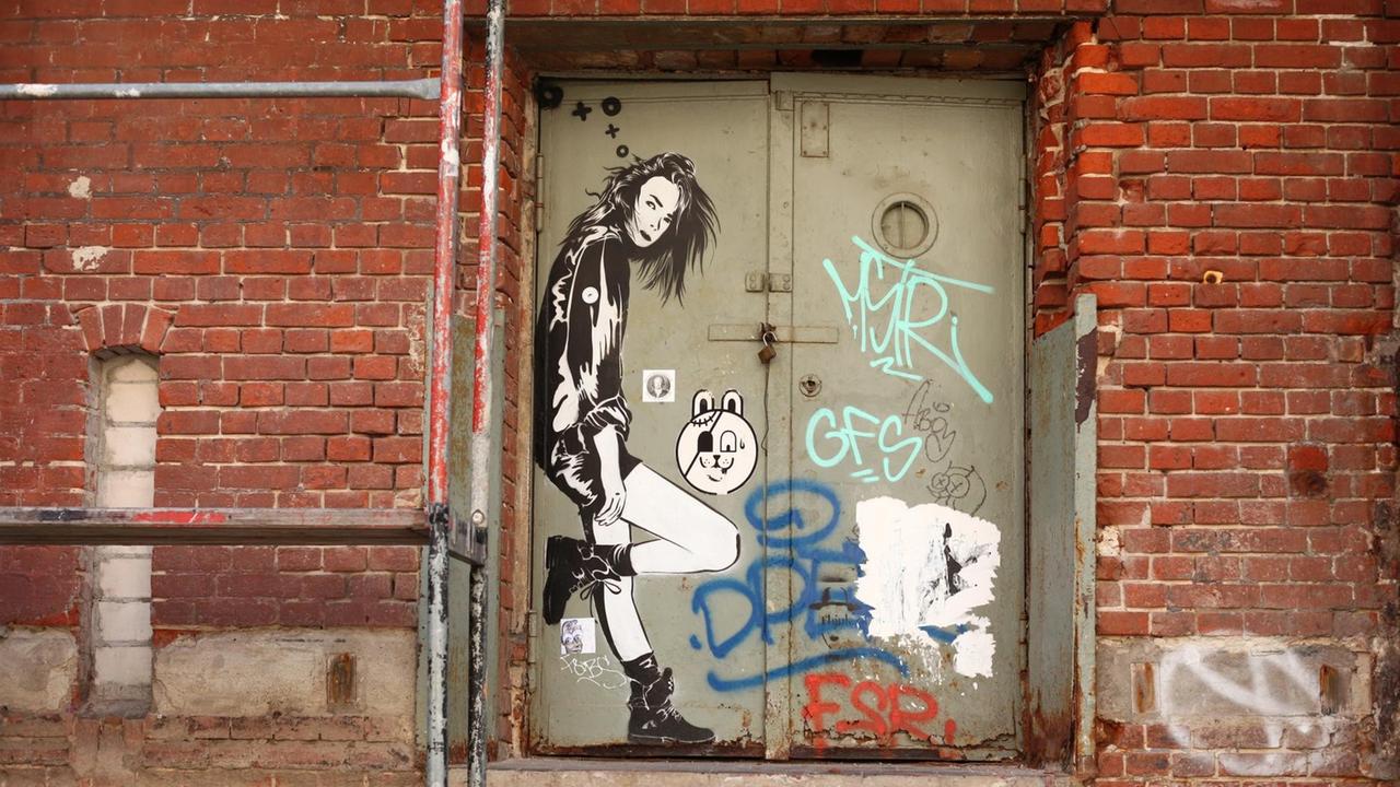 Der Streetart-Künstler XOOOOX hat in der Nähe der U-Bahnstation Gleisdreieck in Berlin auf eine alte Metalltür das Bildnis einer jungen Frau gesprayt.