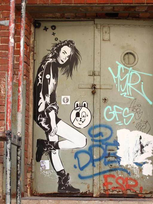 Der Streetart-Künstler XOOOOX hat in der Nähe der U-Bahnstation Gleisdreieck in Berlin auf eine alte Metalltür das Bildnis einer jungen Frau gesprayt.