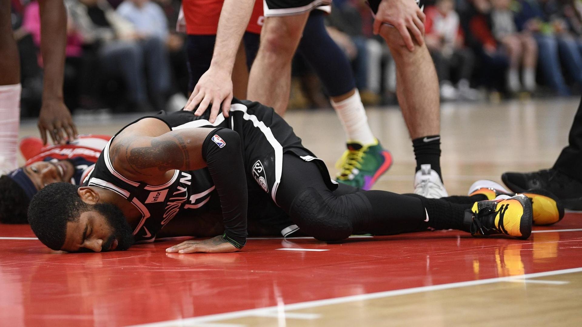 Basketballer Kyrie Irving von den Brooklyn Nets liegt auf dem Boden. Basketballer Kyrie Irving von den Brooklyn Nets liegt auf dem Boden.