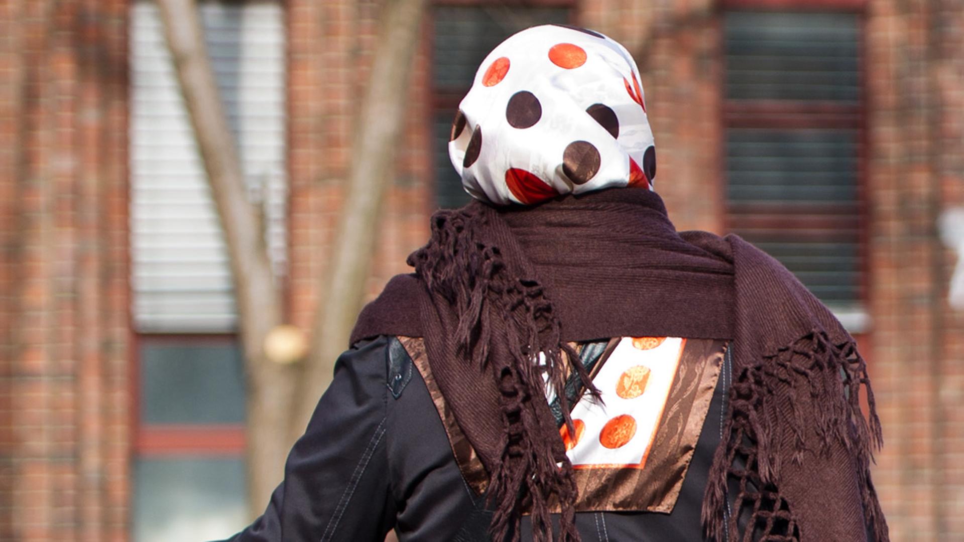 Eine Frau mit Kopftuch steht an einer Straße