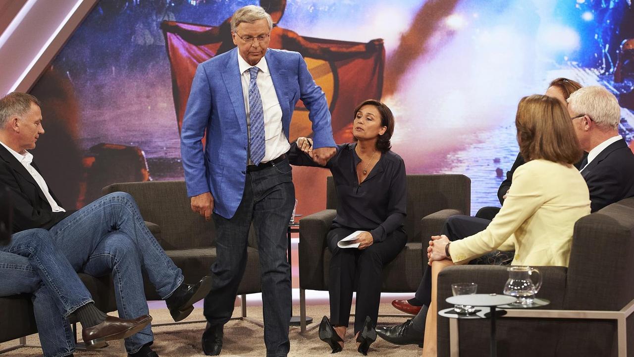 Bosbach ist gerade aufgestanden und geht. Er schüttelt die Hand Maischbergers ab, die ihn zum Bleiben bewegen wollte. Die anderen Talkgäste schauen zu. Bosbach ist gerade aufgestanden und geht. Er schüttelt die Hand Maischbergers ab, die ihn zum Bleiben bewegen wollte. Die anderen Talkgäste schauen zu.