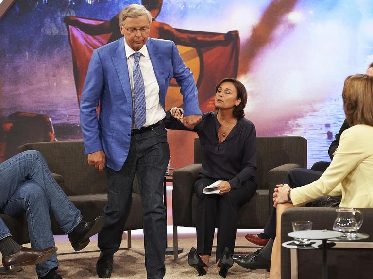 Bosbach ist gerade aufgestanden und geht. Er schüttelt die Hand Maischbergers ab, die ihn zum Bleiben bewegen wollte. Die anderen Talkgäste schauen zu.