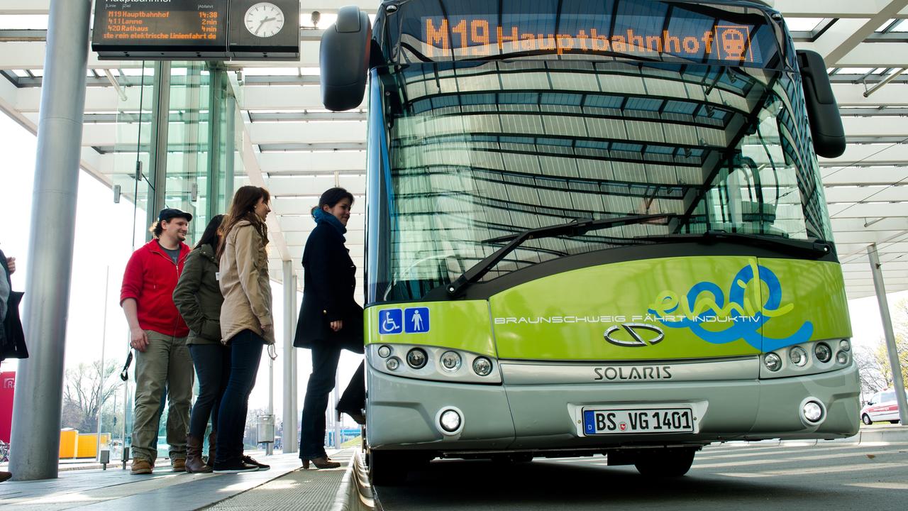 Ein Bus der Braunschweiger Verkehrs AG hält an ein Haltestelle an. Fahrgäste steigen zu, die Akkus werden durch Induktionsschleifen im Boden aufgeladen.