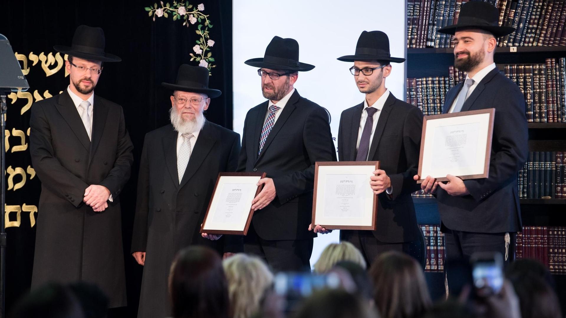 09.10.2018, Berlin: Dayan Chanoch Ehrentreu (2.v.l), Dekan des Rabbinerseminars zu Berlin, übergibt zusammen mit Rabbiner Moishe Halpern (l) bei der Feierlichen Ordination von Rabbinern und Kantoren in der Beth Zion Synagoge im Bezirk Mitte die Urkunden an die ordinierten Rabbis Alexander Kahanovsky (M), Shlomo Sajatz (2.v.r) und Shraga Yaakov Ponomarov (r). Foto: Bernd von Jutrczenka/dpa | Verwendung weltweit 09.10.2018, Berlin: Dayan Chanoch Ehrentreu (2.v.l), Dekan des Rabbinerseminars zu Berlin, übergibt zusammen mit Rabbiner Moishe Halpern (l) bei der Feierlichen Ordination von Rabbinern und Kantoren in der Beth Zion Synagoge im Bezirk Mitte die Urkunden an die ordinierten Rabbis Alexander Kahanovsky (M), Shlomo Sajatz (2.v.r) und Shraga Yaakov Ponomarov (r). Foto: Bernd von Jutrczenka/dpa | Verwendung weltweit