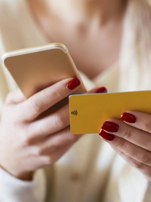 Blonde woman using smartphone and using bank card at home model released Symbolfoto property released PUBLICATIONxINxGERxSUIxAUTxHUNxONLY EBSF02398
