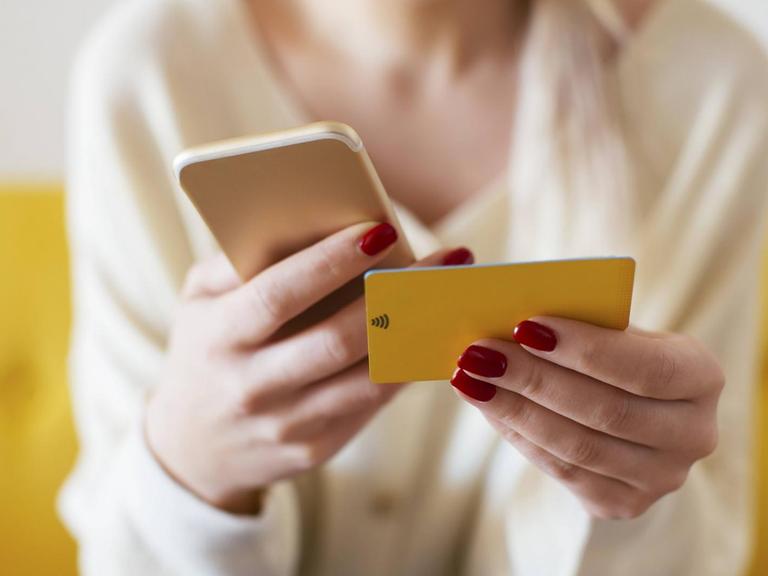 Blonde woman using smartphone and using bank card at home model released Symbolfoto property released PUBLICATIONxINxGERxSUIxAUTxHUNxONLY EBSF02398