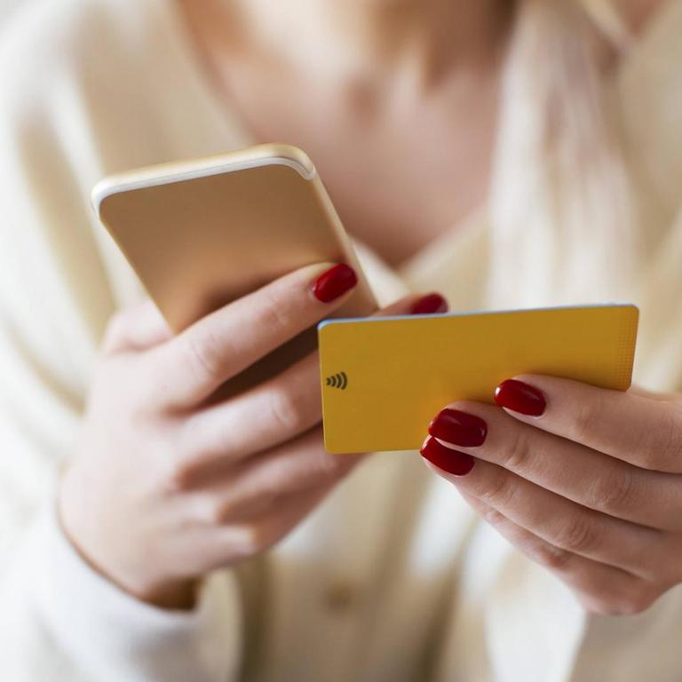 Blonde woman using smartphone and using bank card at home model released Symbolfoto property released PUBLICATIONxINxGERxSUIxAUTxHUNxONLY EBSF02398