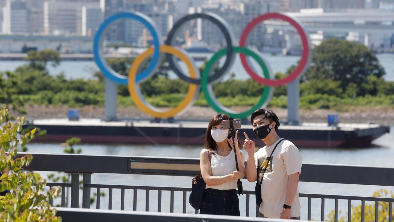 Ein paar macht ein Foto vor den Olympischen Ringen in Tokio. Ein paar macht ein Foto vor den Olympischen Ringen in Tokio.