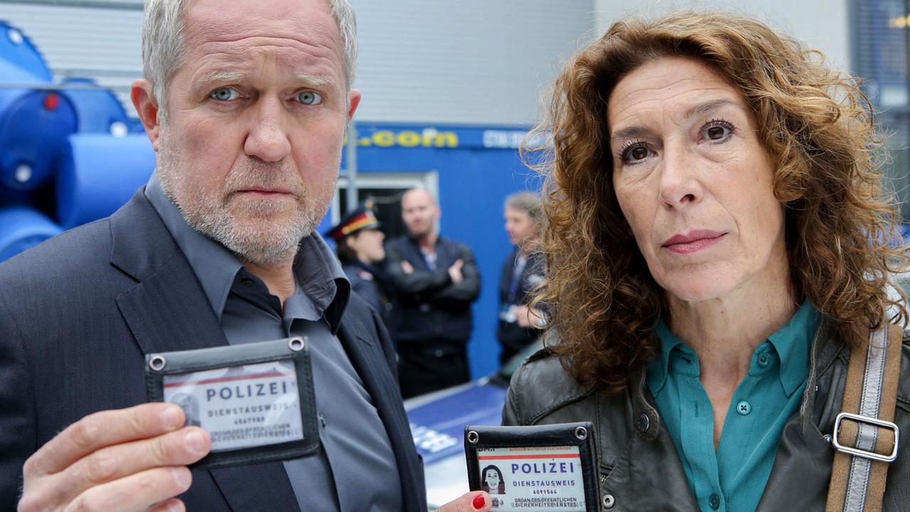 Aus der Tatort-Folge "Gier" (2015): Die Kommissare Moritz Eisner (Harald Krassnitzer) und Bibi Fellner (Adele Neuhauser) müssen sich ausweisen, und das auch noch gleichzeitig Aus der Tatort-Folge "Gier" (2015): Die Kommissare Moritz Eisner (Harald Krassnitzer) und Bibi Fellner (Adele Neuhauser) müssen sich ausweisen, und das auch noch gleichzeitig