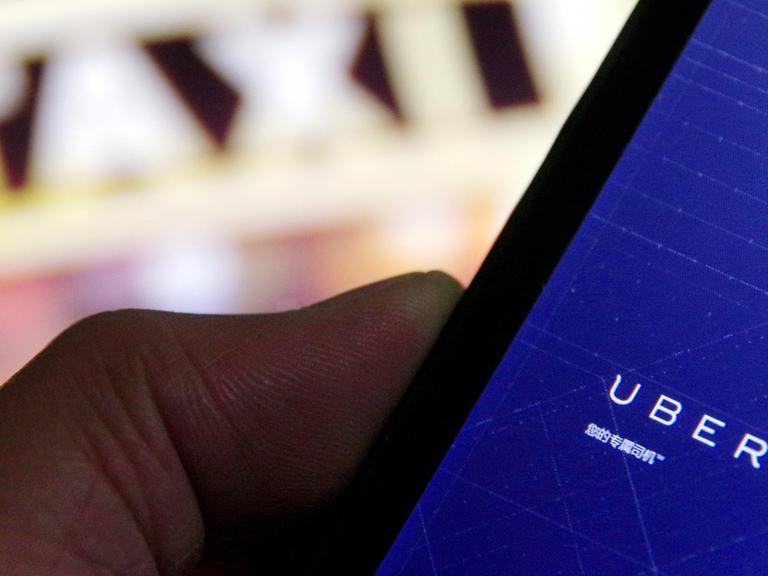 Ein Mann benutzt auf seinem Smartphone Uber, die Taxi-App.