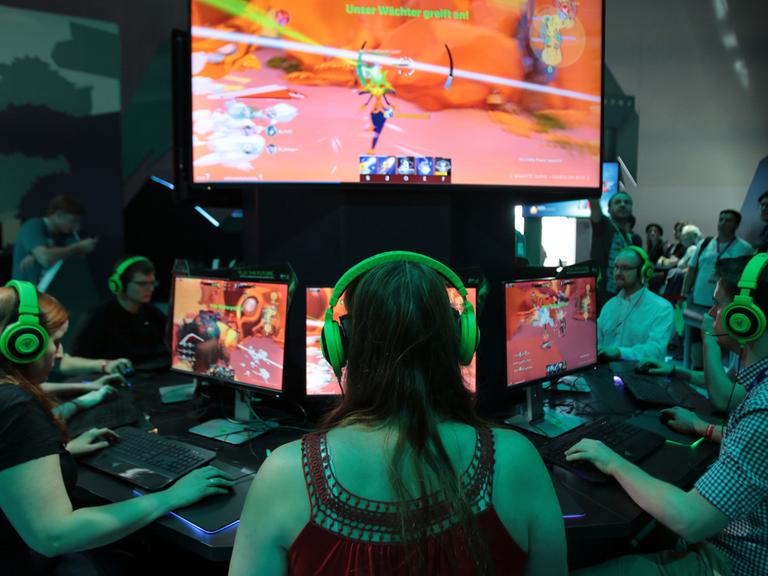 Besucher der Gamescom testen in Köln das Computer Spiel Gigantic.
