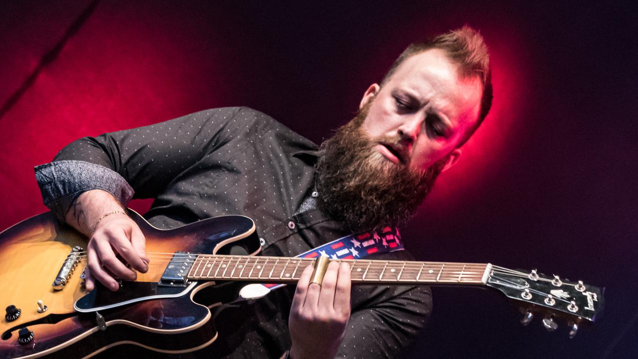 Ein Mann steht auf einer Bühne und spielt Gitarre Ein Mann steht auf einer Bühne und spielt Gitarre