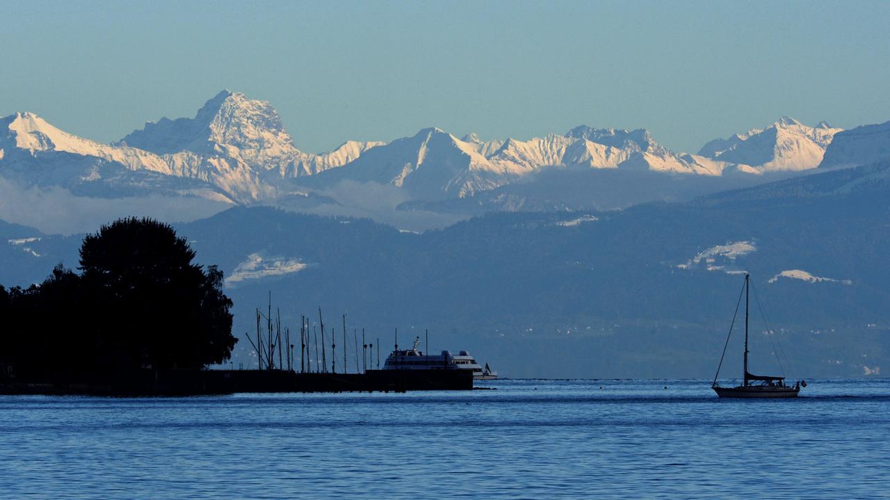 Ein Segelboot fährt am 11.10.2013 vor Meersburg (Baden-Württemberg) kurz vor Sonnenuntergang auf dem Bodensee, während im Hintergrund die Schweizer Alpen zu sehen sind. Ein Segelboot fährt am 11.10.2013 vor Meersburg (Baden-Württemberg) kurz vor Sonnenuntergang auf dem Bodensee, während im Hintergrund die Schweizer Alpen zu sehen sind.