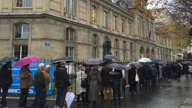 Menschen stehen mit Regenschirmen vor einem Rathaus in Paris Menschen stehen mit Regenschirmen vor einem Rathaus in Paris
