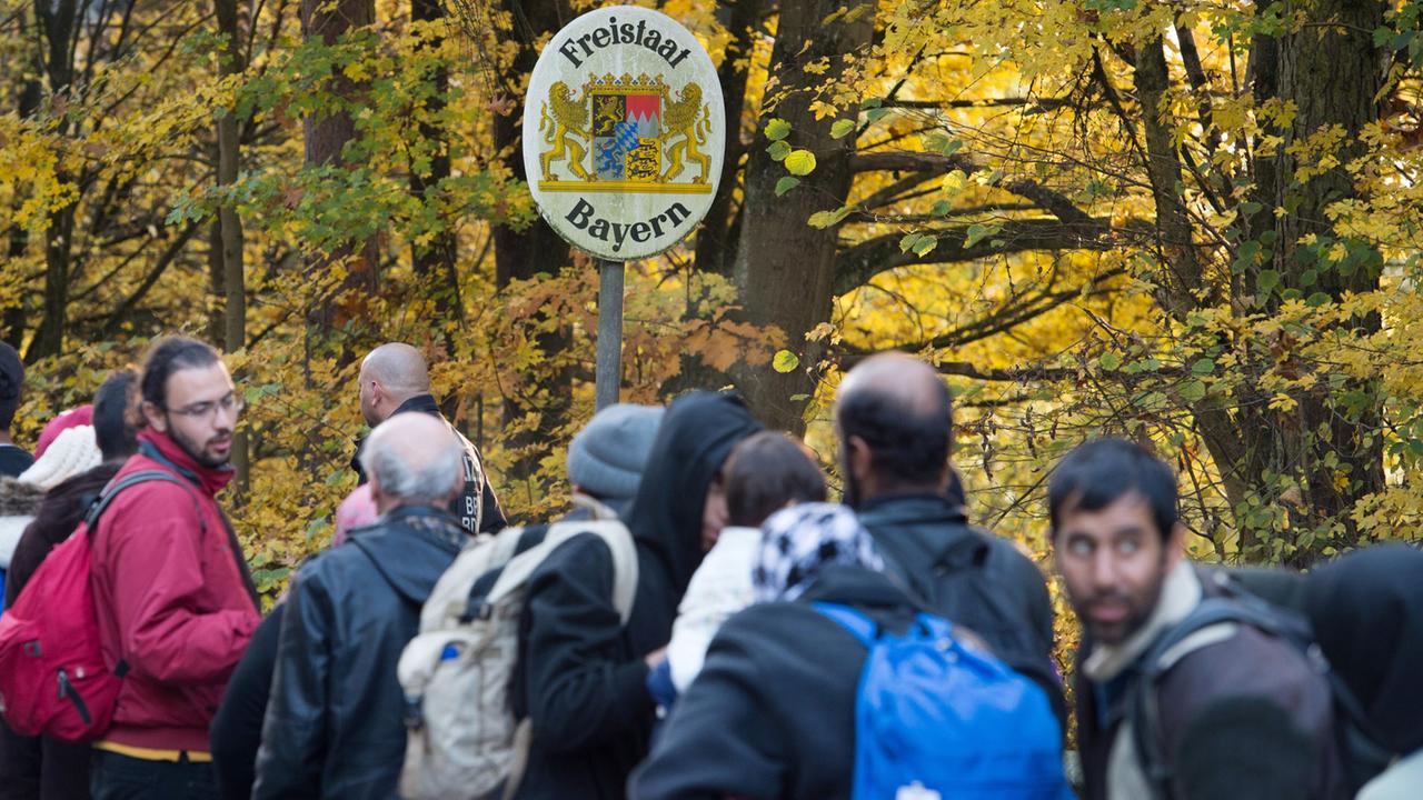 Flüchtlinge warten nahe Passau (Bayern) an der deutsch-österreichischen Grenze vor einem Schild mit der Aufschrift "Freistaat Bayern". Flüchtlinge warten nahe Passau (Bayern) an der deutsch-österreichischen Grenze vor einem Schild mit der Aufschrift "Freistaat Bayern".