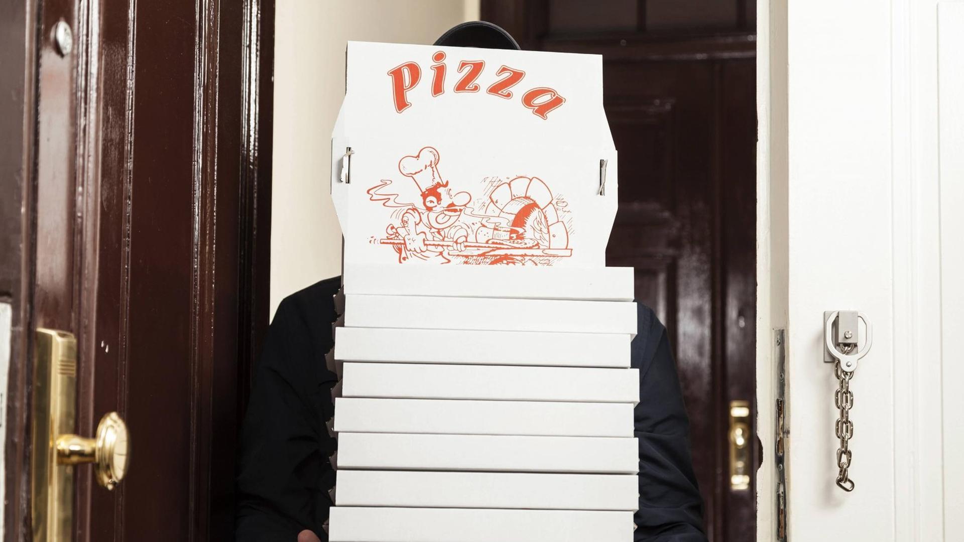 Ein Pizza Bote mit einem Stapel Pizzakartons Ein Pizza Bote mit einem Stapel Pizzakartons
