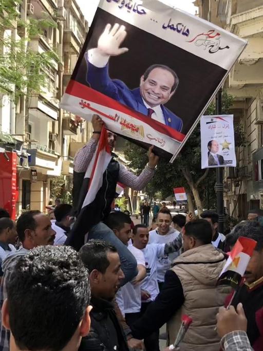 Demontranten während der Präsidentschaftswahl in Ägypten. Vor einem Wahllokal halten sie ein Bild von Präsident al-Sisi in die Höhe.