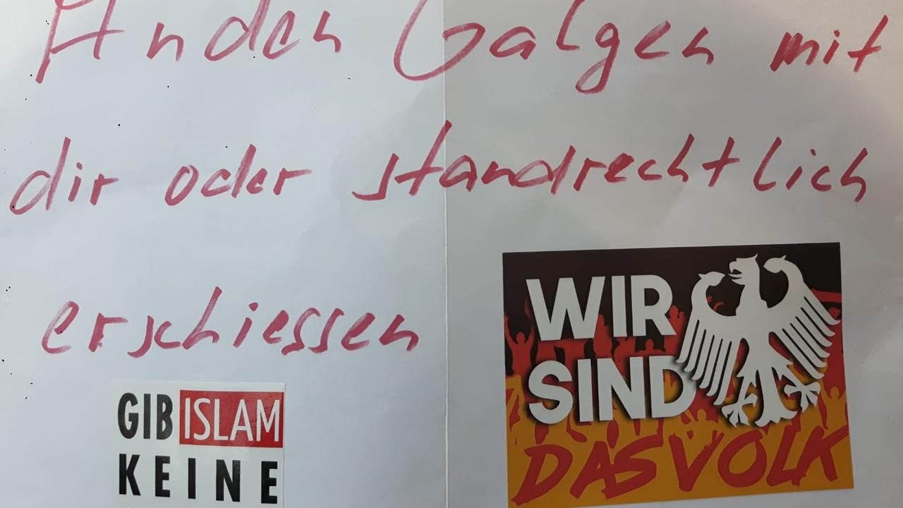 Das Foto zeigt einen anonymen Drohbrief mit dem handschriftlichen, roten Schriftzug: "An den Galgen mit dir oder standrechtlich erschießen"