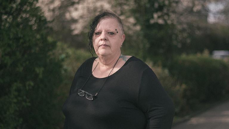 Eine Frau in schwarzer Kleidung steht in einem Park. Eine Frau in schwarzer Kleidung steht in einem Park.