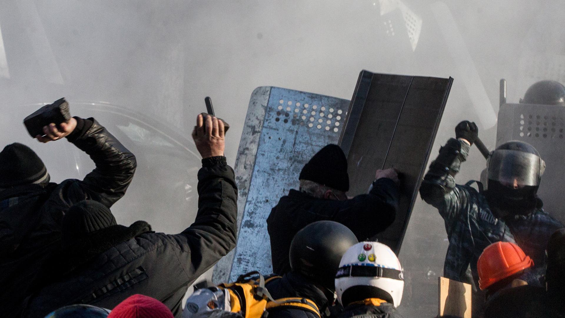 Steinewerfende Demonstranten stehen sich mit Polizisten gegenüber. Steinewerfende Demonstranten stehen sich mit Polizisten gegenüber.
