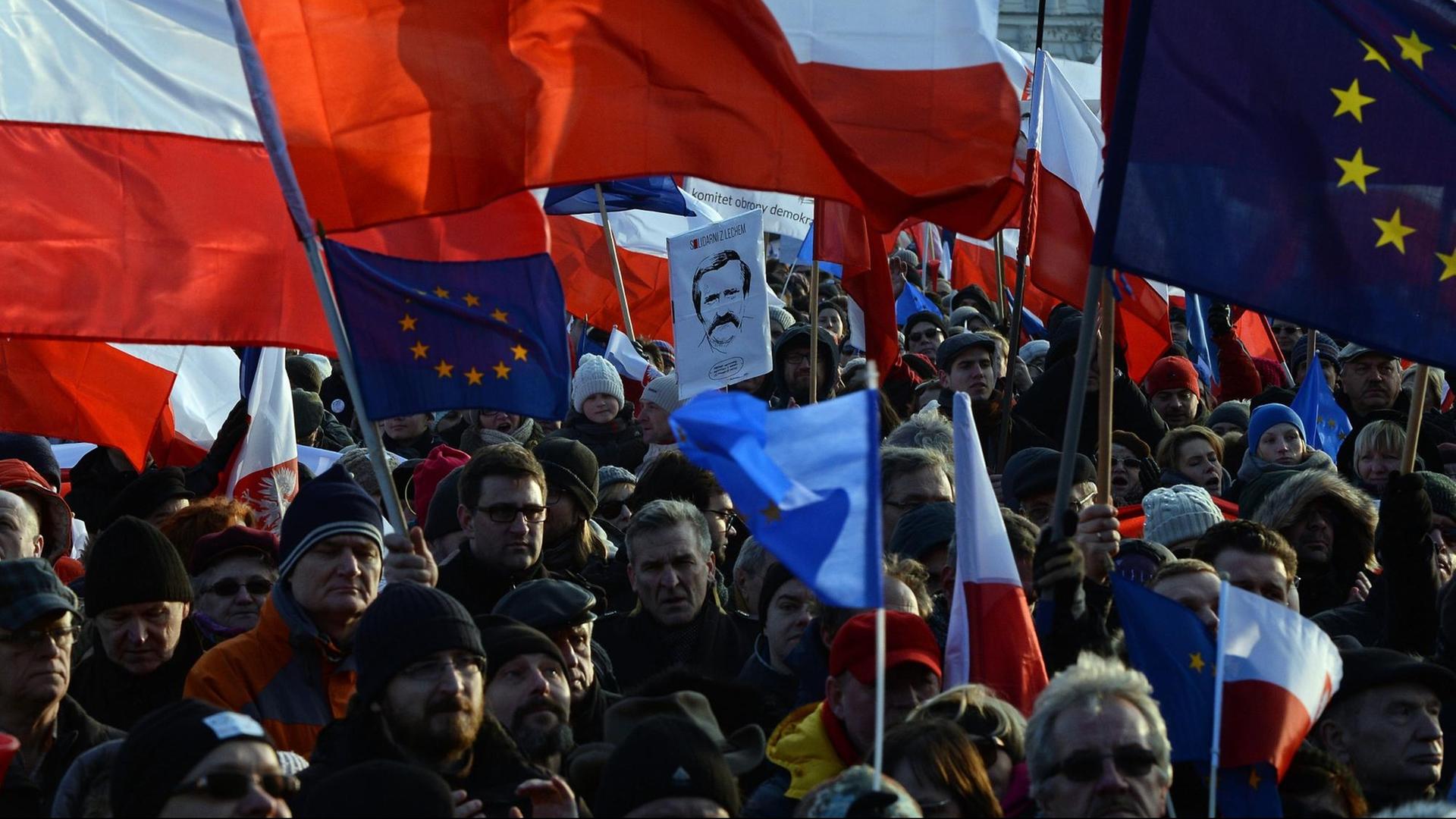 Demonstranten protestieren in Warschau gegen die Regierung. Viele Menschen schwenken die Fahnen Polens und der EU. Demonstranten protestieren in Warschau gegen die Regierung. Viele Menschen schwenken die Fahnen Polens und der EU.