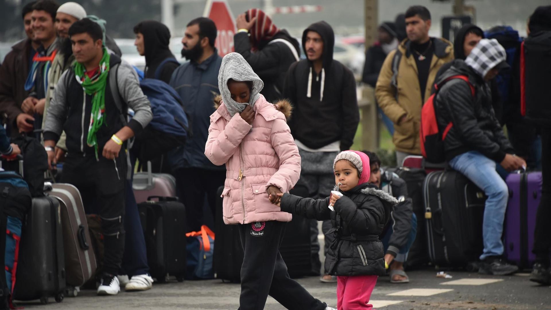 Flüchtlinge warten mit ihrem Gepäck darauf, vom illegalen Lager in Calais in Aufnahmezentren in ganz Frankreich gebracht zu werden. Flüchtlinge warten mit ihrem Gepäck darauf, vom illegalen Lager in Calais in Aufnahmezentren in ganz Frankreich gebracht zu werden.