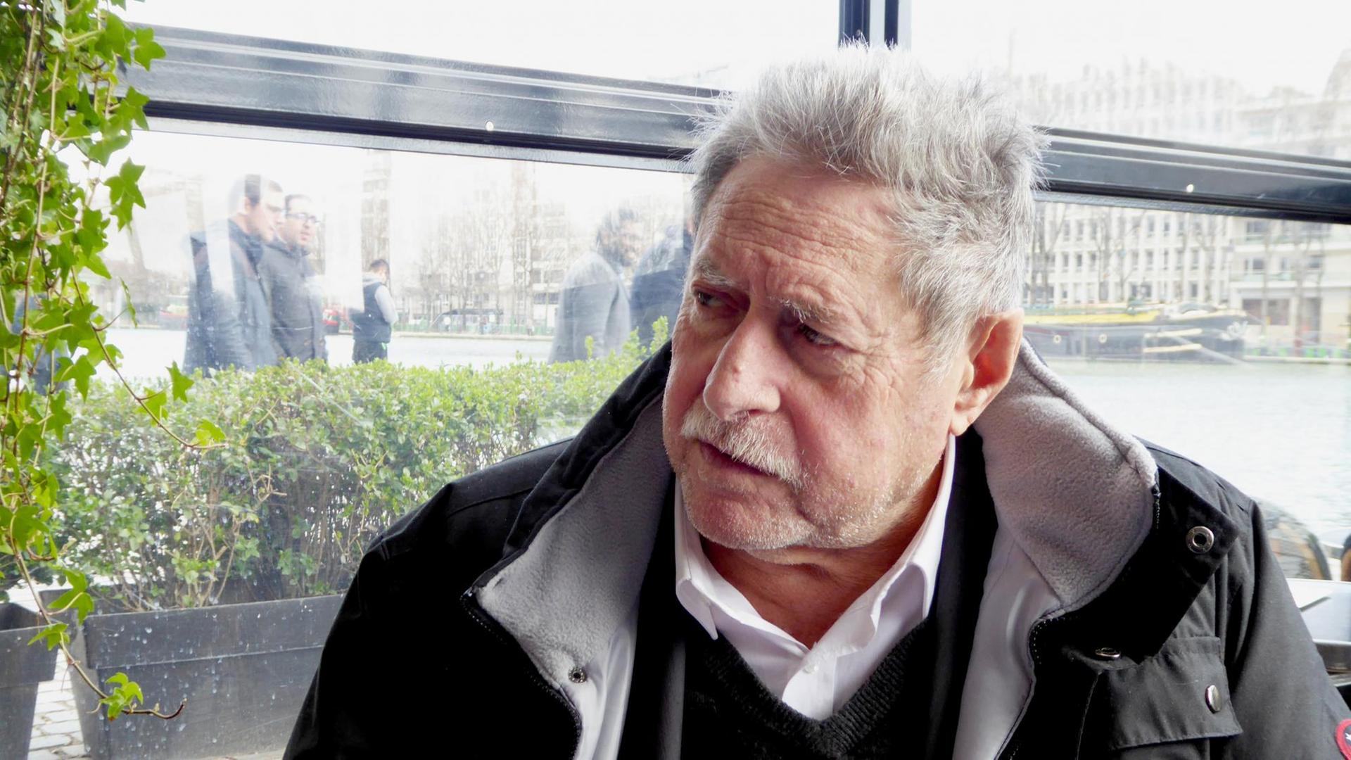 Porträtaufnahme Sammy Ghozlan: ein älterer Mann mit weiß-grauem Haar und Schnurrbart und dunkler Jacke. Porträtaufnahme Sammy Ghozlan: ein älterer Mann mit weiß-grauem Haar und Schnurrbart und dunkler Jacke.