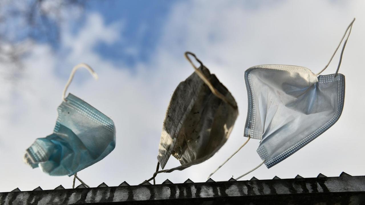 Gebrauchte Atemschutzmasken hängen an einem Zaun. Gebrauchte Atemschutzmasken hängen an einem Zaun.
