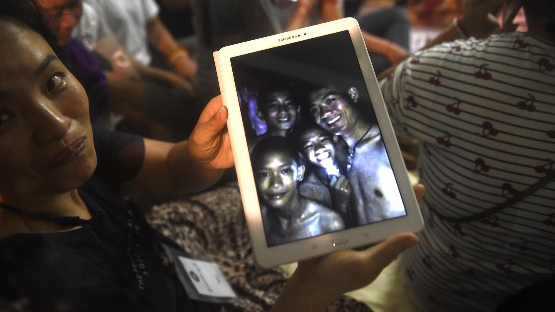 Ein Familienmitglied zeigt ein Bild von Kindern aus einer Jugendfußballmannschaft, die tagelang in einer Höhle in Thailand eingeschlossen waren. Ein Familienmitglied zeigt ein Bild von Kindern aus einer Jugendfußballmannschaft, die tagelang in einer Höhle in Thailand eingeschlossen waren.