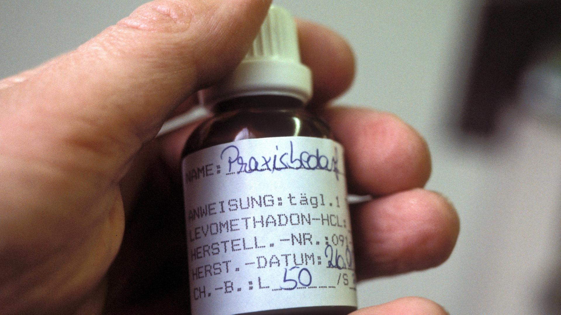 Methadonfläschchen in der Hand eines Drogenpatienten Methadonfläschchen in der Hand eines Drogenpatienten
