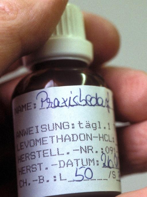 Methadonfläschchen in der Hand eines Drogenpatienten