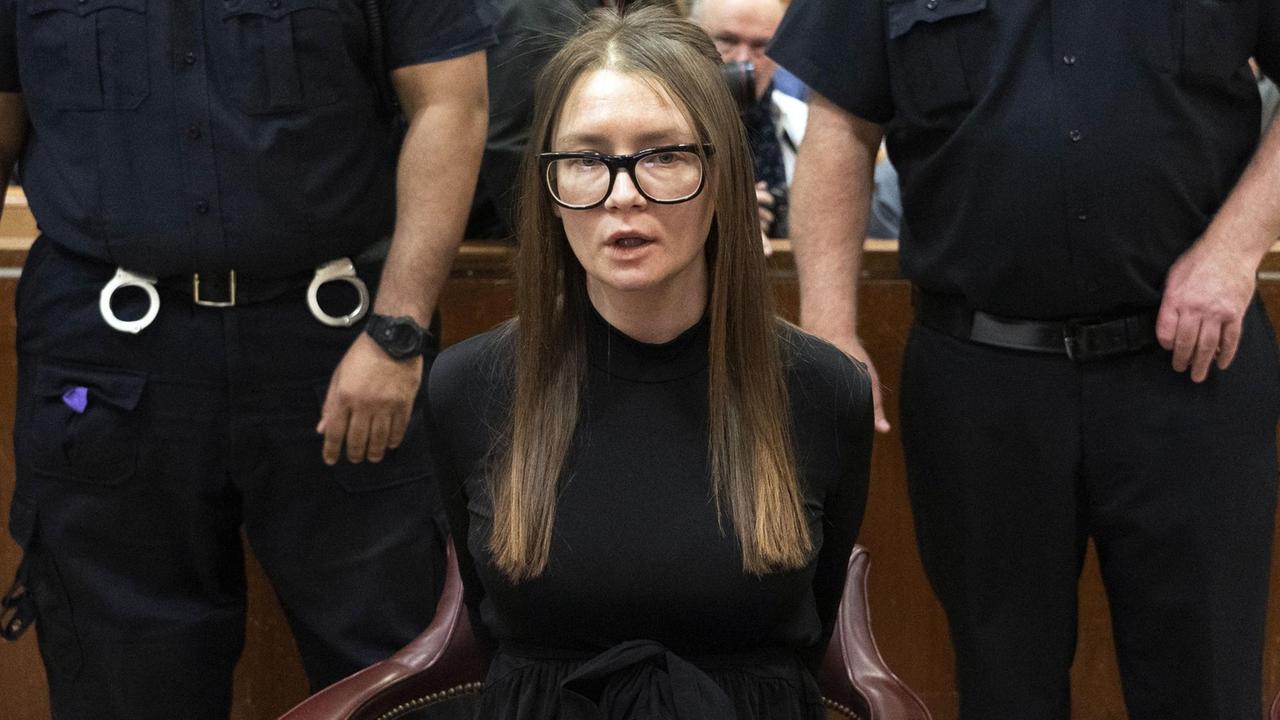Anna Sorokin sitzt in Handschellen im Gerichtssaal, hinter ihr zwei Polizisten.