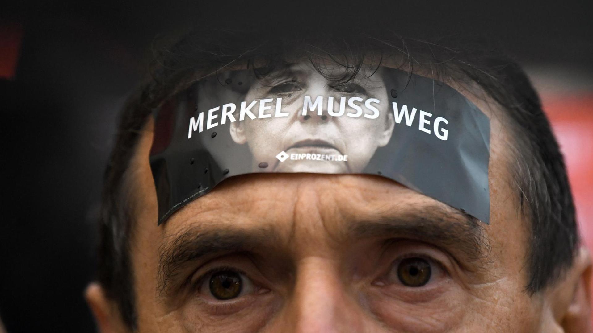 Ein Demonstrant protestiert am 06.09.2017 in Finsterwalde (Brandenburg) auf dem Marktplatz gegen Bundeskanzlerin Angela Merkel (CDU) während einer Wahlkampfveranstaltung der CDU mit einem Aufkleber auf seiner Stirn. Foto: Ralf Hirschberger/dpa-Zentralbild/ZB | Verwendung weltweit Ein Demonstrant protestiert am 06.09.2017 in Finsterwalde (Brandenburg) auf dem Marktplatz gegen Bundeskanzlerin Angela Merkel (CDU) während einer Wahlkampfveranstaltung der CDU mit einem Aufkleber auf seiner Stirn. Foto: Ralf Hirschberger/dpa-Zentralbild/ZB | Verwendung weltweit