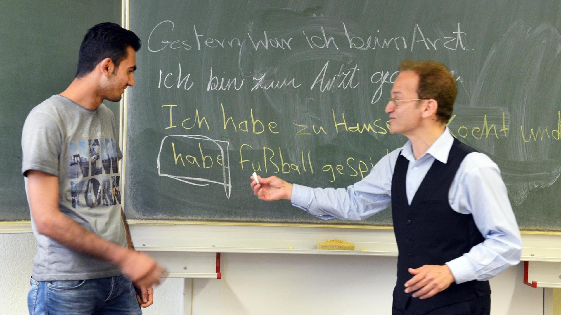 In der Volkshochschule in Leipzig steht Samer Alale aus Syrien (l) mit seinem Lehrer Mounir Taoubi beim Deutsch-Unterricht im Integrationskurs an der Tafel.