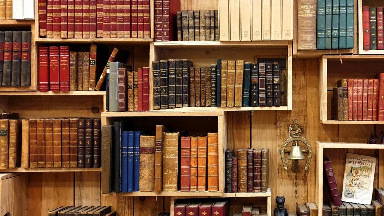 In einer Regalwand aus Holzkästen stehen alte Bücherbände. In einer Regalwand aus Holzkästen stehen alte Bücherbände.
