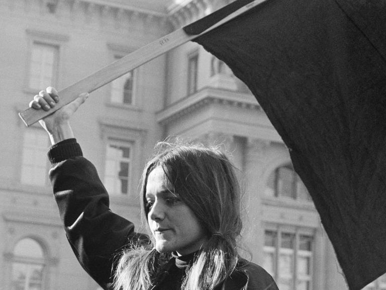 Das Schwarz-weiß-Foto von 1969 zeigt eine junge blonde Frau mit einer Fahne in der Hand.