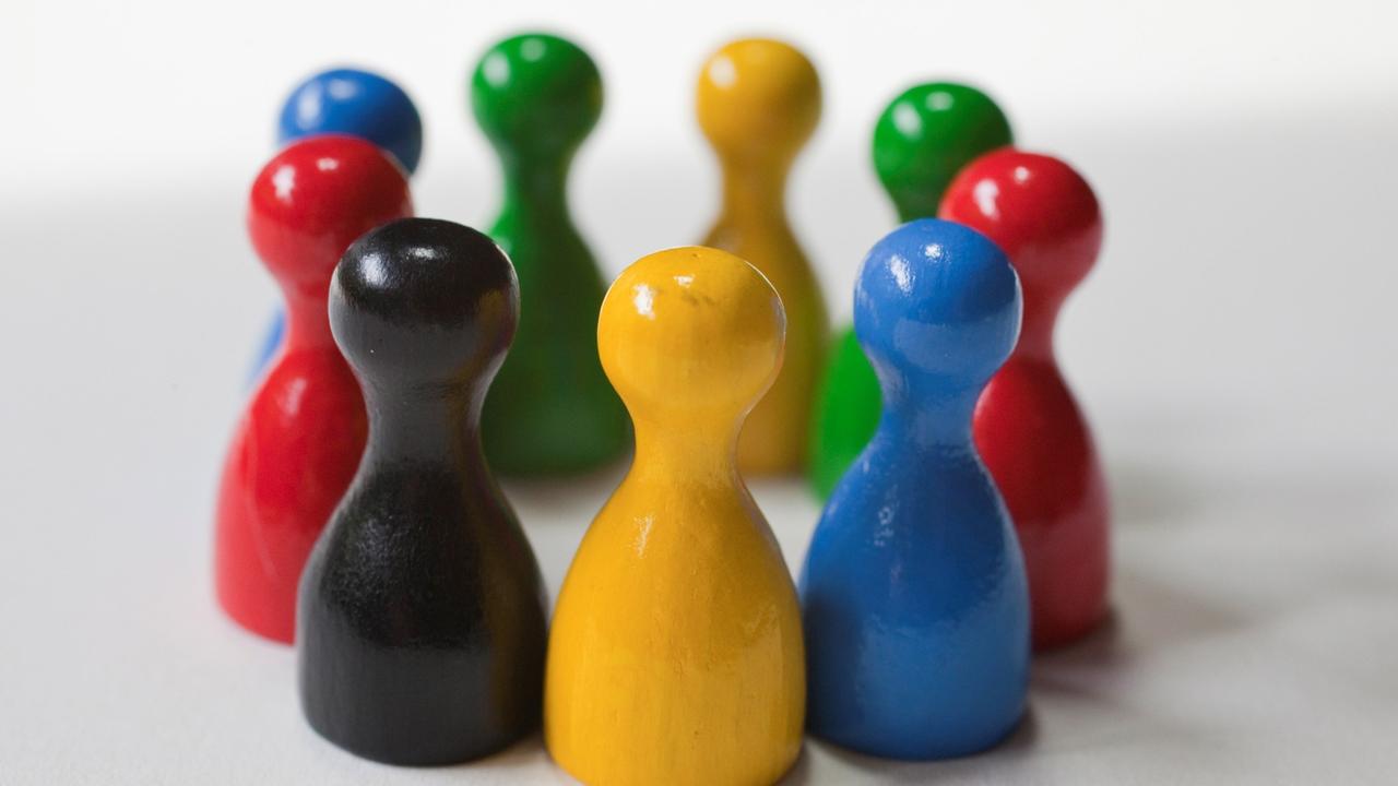 Spielfiguren in unterschiedlichen Farben stehen im Kreis Spielfiguren in unterschiedlichen Farben stehen im Kreis