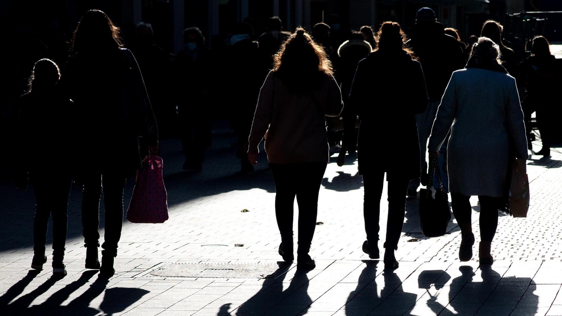 Silhouetten von Menschen mit Einkaufstüten - die meisten sind von hinten zu sehen Silhouetten von Menschen mit Einkaufstüten - die meisten sind von hinten zu sehen