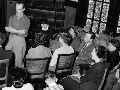 "Wunderheiler" Bruno Gröning (l, stehend) spricht 1955 in Düsseldorf in einer Privatversammlung vor geladenen Gästen.